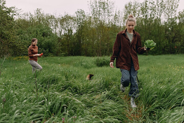 Middle age woman walking outdoors in green field holding fresh vegetables, promoting active and...