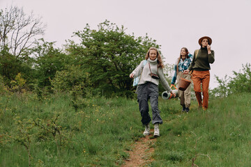 Active middle age woman hiking outdoors with friends in green nature, enjoying wellness, fitness,...