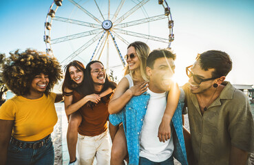 Naklejka na ściany i meble Multiracial friends having fun walking in front of ferris wheel at summer vacation - Friendship concept with guys and girls hanging outside on a sunny day - Summertime holidays life style concept