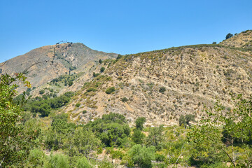 Dry Hillside with Sparse Vegetation under Clear Blue Sky
