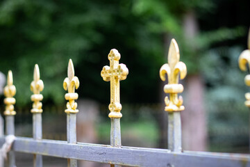Element metal fence with decorative golden finials in form of crosses and fleurs-de-lis adding...