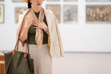 Close up of young Caucasian woman looks at an exhibition of paintings in a modern gallery in...