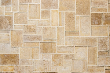 Natural stone masonry with bricks of various sizes and shapes creating a decorative and textured background with a unique, natural pattern and organic shades