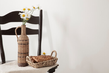 daisies in a vintage bottle and baked goods in a basket on a vintage chair