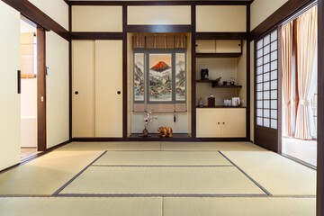 Japanese traditional room with tatami mat flooring and sliding doors featuring scenic wall hanging...