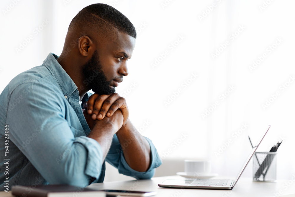 Poster thoughtful black writer working with laptop at home office. african american freelancer man sitting 