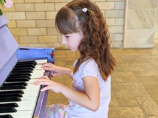 Little girl is playing old piano