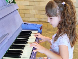 Little girl is playing old piano