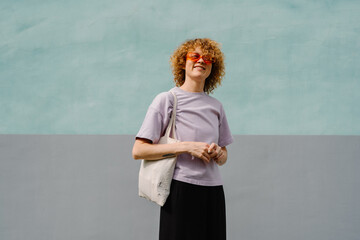 Confident woman smiling in lavender shirt and orange sunglasses