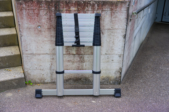 High angle view of aluminium telescoping ladder leaned against concrete wall outdoors at Swiss city of Z&uuml;rich on a summer day. Photo taken June 23rd, 2025, Zurich, Switzerland.