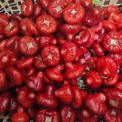 Fresh red fruits in a woven basket on a rustic wooden surface
