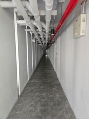 Industrial Pipework and Modern Flooring in a Long Corridor Space