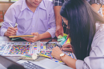 Team graphic designer checking print quality of media graphics proof print and color guides in printing industry. Selected focus