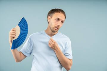 Exhausted man suffering from heat, fanning, looking worn out. Tired middle aged male standing...