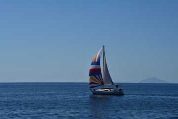 Colorful Sailboat on a Tranquil Sea Under a Clear Blue Sky