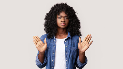 Irritated young black woman showing stop gesture with both palms over grey studio background, copy...