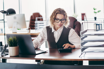 Confident female professional working in a stylish office, conducting corporate tasks with focus...