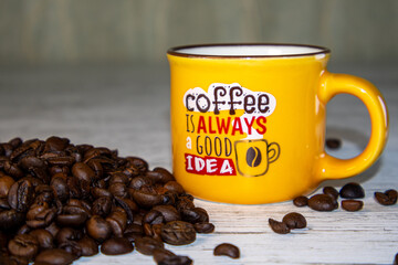 A bunch of coffee beans. A yellow cup of coffee.