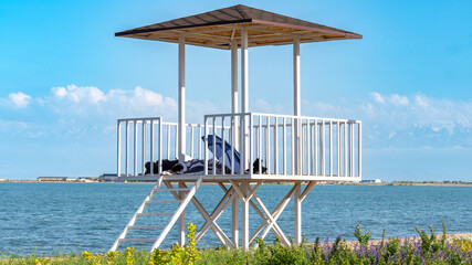 Lifeguard tower by the lake with mountains in the background
