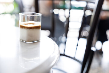 Cup of milk dirty coffee on white marble table by the window.
