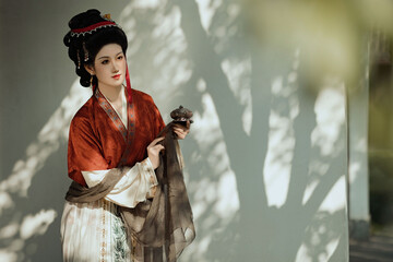 Elegant woman in traditional attire holding a decorative object.