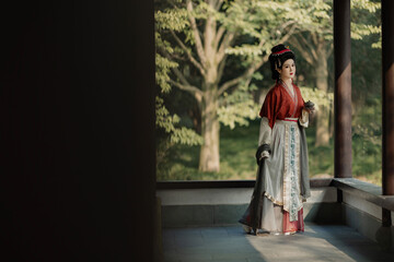 Asian female model in traditional clothing outdoors.