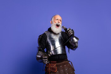 A passionate bearded man in metallic knight armor singing on a purple background