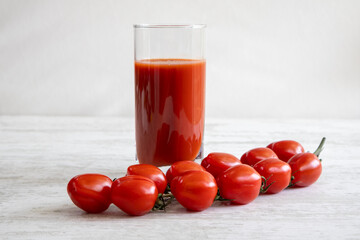 Tomato juice. Cherry tomato. White wood texture table.