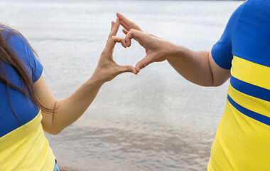 Love Ukraine concept. Hands of man woman in yellow and blue T-shirts folded in shape of heart. Independence Day, Constitution Day. Family, unity, support, proud. Ukrainian