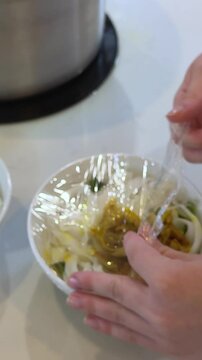 Pouring hot meatballs into a bowl with a plastic wrap base using a round spoon from a hot pot at a meatball vendor's cart. Meatballs are a popular food in Indonesia