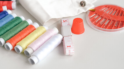 Colorful sewing threads and measuring tape on clean white background