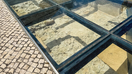 Archaeological relics beneath a transparent glass floor evoke ancient mysteries, ideal for Urban...