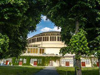 Historic Centennial Hall framed by vibrant green trees, displaying timeless beauty against a sunny...