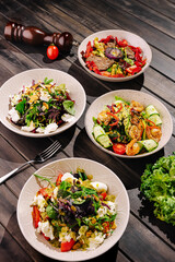 Colorful salad bowls displayed on a wooden table with fresh ingredients