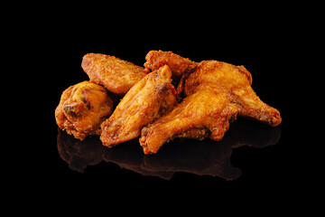 Crispy fried chicken wings arranged on a dark reflective surface