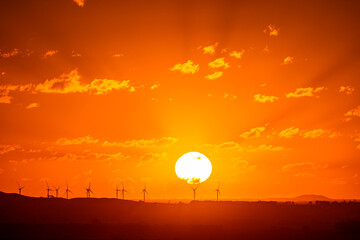 Sunset over wind turbines with horizon over land, Camperdown, Victoria, Australia