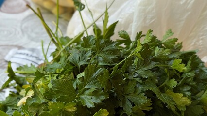 Bunch of vibrant green parsley leaves placed on a white patterned tablecloth, ready for cooking or...