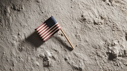Symbolic Moon Landing Anniversary image of small US flag lying alone on lunar surface in harsh light ideal for memory, solitude themes and conceptual visuals