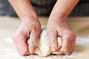Culinary, cooking, baking concept. Female hands kneading dough, unrecognizable woman grandmother in...