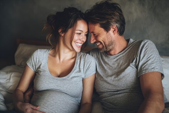 A lovely expectant mother and her attractive partner are joyfully sharing time in bed while he listens to their baby - Powered by Adobe