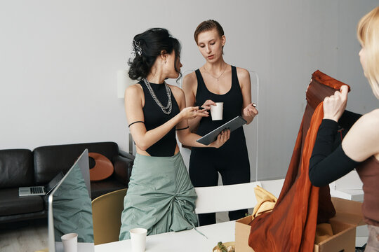 two young women colleagues discussing work in a modern workplace, socializing and collaborating as Gen Z friends in a business environment with casual attire and coffee