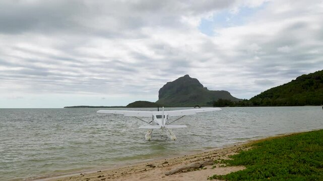 White floatplane on shallow waters of remote island paradise with dramatic stormy sky.Adventure travel. Seaplane with majestic mountain backdrop