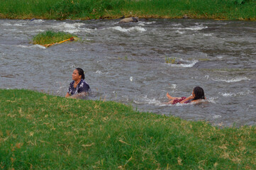 As the daughter floats on her back in the river’s current, the mother is carried gently toward...