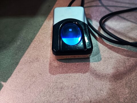 Fingerprint reader with black cable isolated on grey table. Identity verification and access control concept.