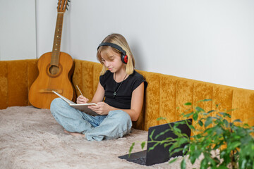 Preteen girl writing music notes during virtual lesson