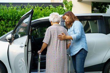 Caregiver help Asian elderly woman disability patient use walker to get in car.
