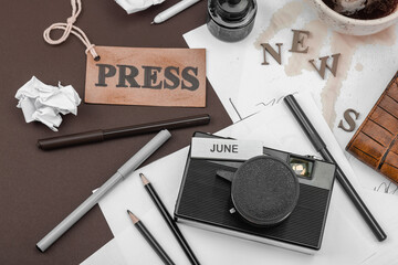 Creative flat lay with vintage camera, press tag, ink bottle, spilled coffee, and messy papers