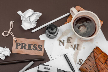 Creative flat lay with vintage camera, press tag, ink bottle, spilled coffee, and messy papers