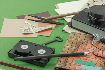 Flat lay with vintage camera, cassette, notebook, key and research tools on green background