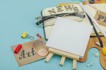 Flat lay of press badge, vintage camera, art supplies, notebook, and exhibition label